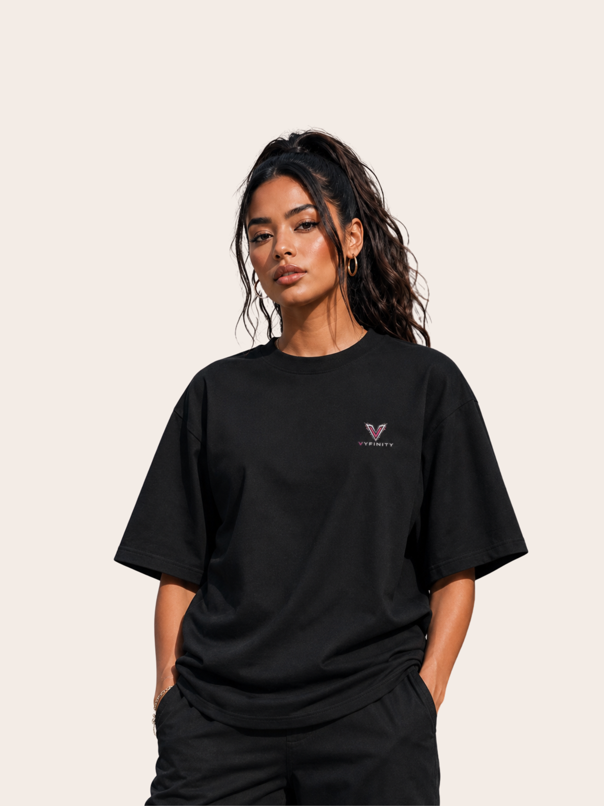 Schwarzes VYFINITY Oversized T-Shirt an einem weiblichen Model, Vorderansicht mit kleinem VYFINITY-Logo auf der Brust. Minimalistischer Premium-Streetwear-Look mit lockerem Schnitt vor hellem, neutralem Studiohintergrund.