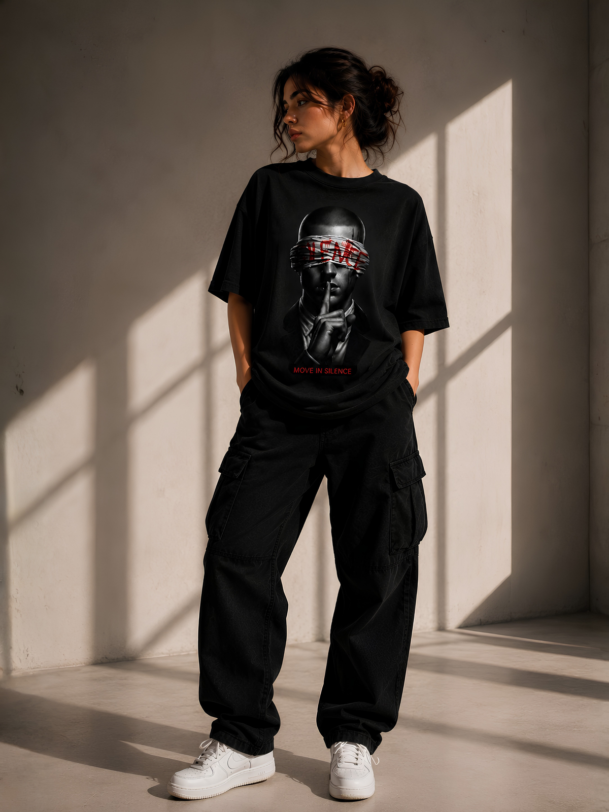 Lifestyle-Aufnahme einer Frau mit schwarzem Vyfinity Oversized-T-Shirt. Das Premium-Streetwear-Shirt zeigt einen markanten Frontprint mit einem geheimnisvollen Portrait sowie den Schriftzug „MOVE IN SILENCE“ – moderner Oversized-Look für Damen und Herren.