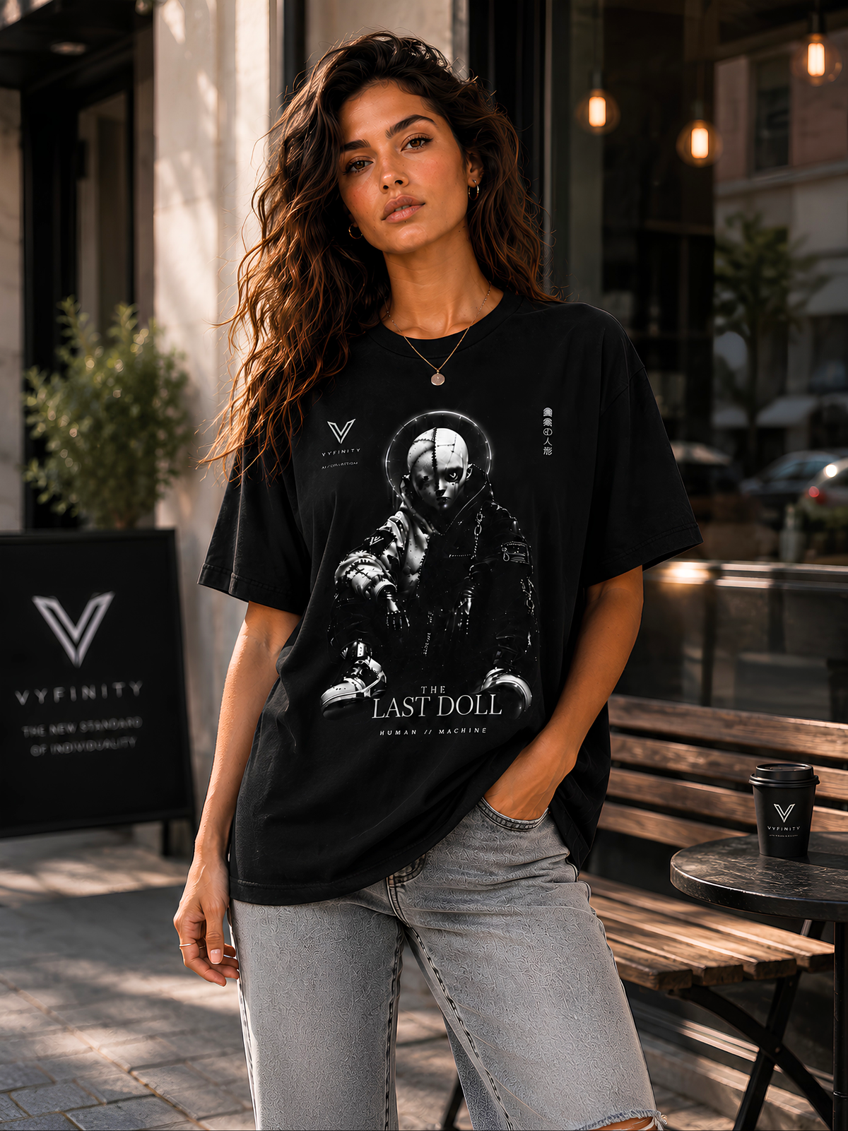 VYFINITY „The Last Doll“ schwarzes Streetwear-T-Shirt an weiblichem Model mit futuristischem Human-Machine-Puppenmotiv, fotografiert in urbanem Lifestyle-Ambiente.
