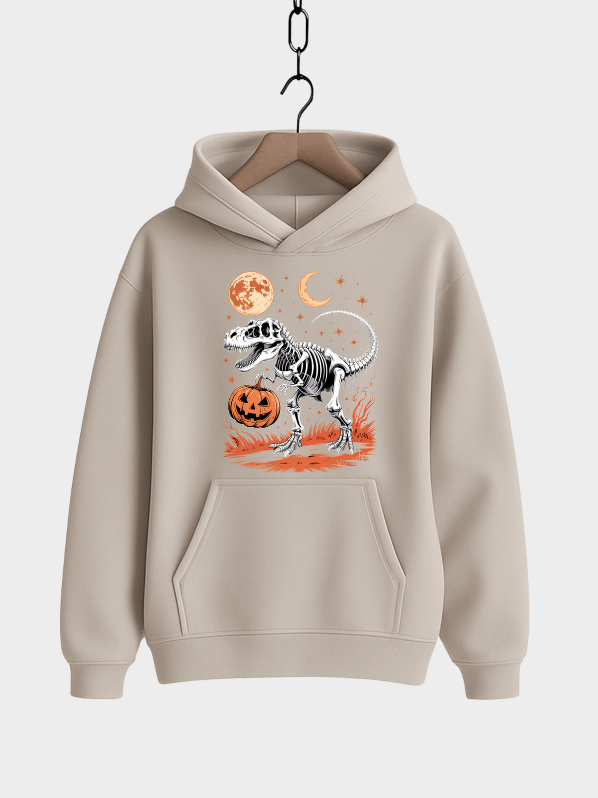 Beigefarbener Halloween Hoodie auf Kleiderbügel mit T-Rex-Skelett Motiv, orangem Kürbis, Vollmond, Halbmond und Sternen.