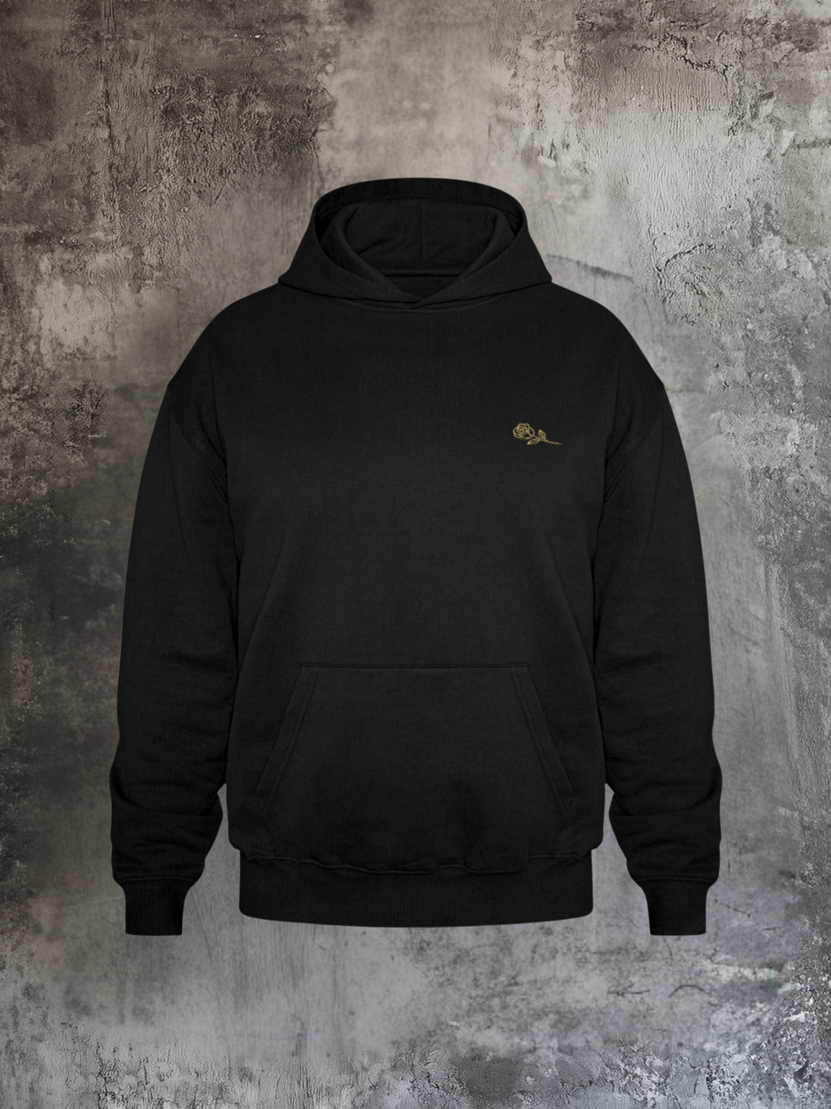 Schwarzer Hoodie mit dezentem goldenen Rosenstick auf der linken Brust, fotografiert vor rauer Betonwand. Minimalistisches Streetwear-Design mit Fronttasche und Kapuze, zeitlos und edel.