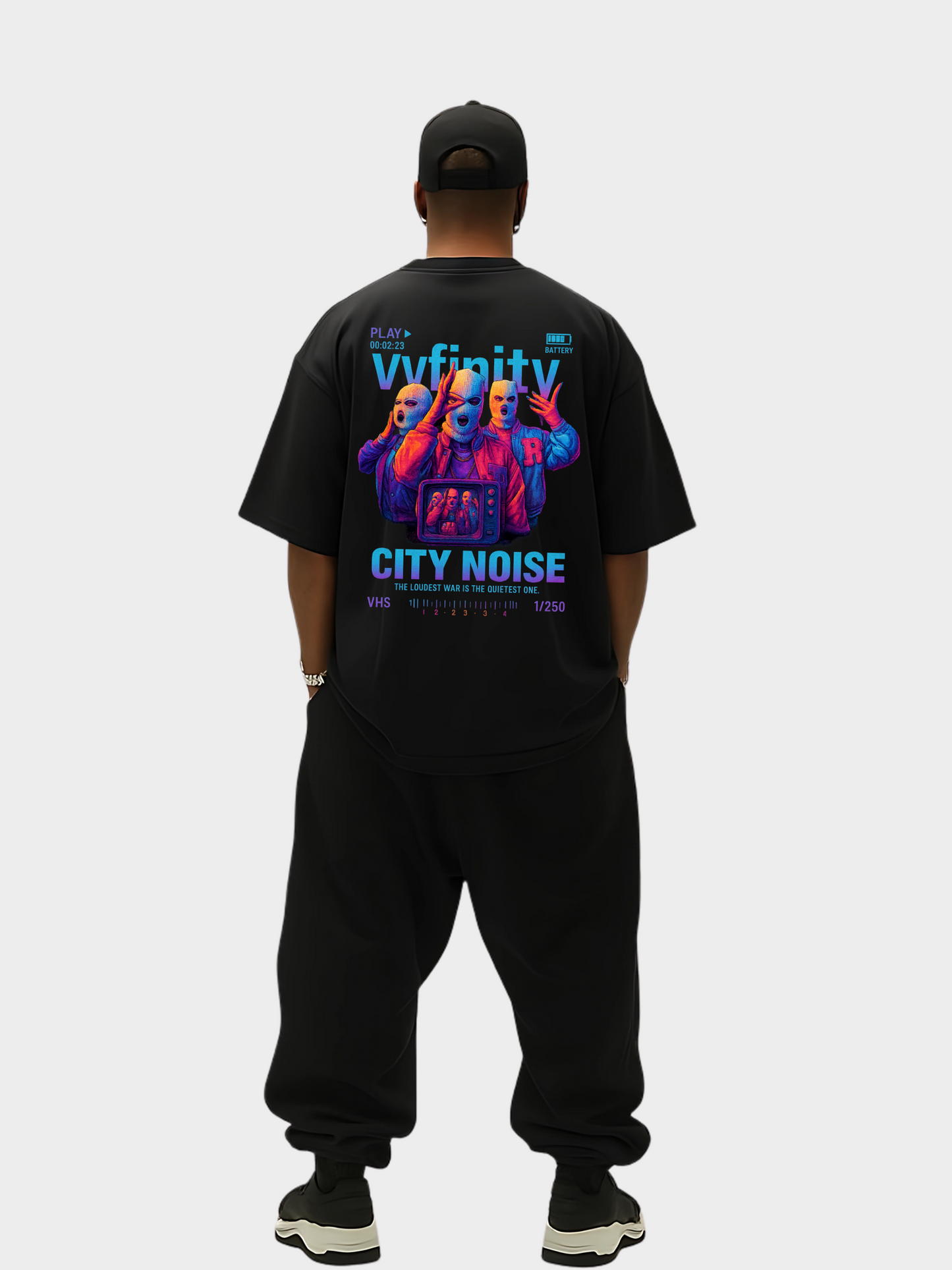 Vyfinity City Noise T-Shirt in Schwarz, Oversized Fit, Rückseite, getragen von einem Model in kompletter Streetwear-Ansicht. Auffälliger Rückenprint mit drei maskierten Figuren im VHS-Design und leuchtenden Farben. Limitierte Edition 1/250.