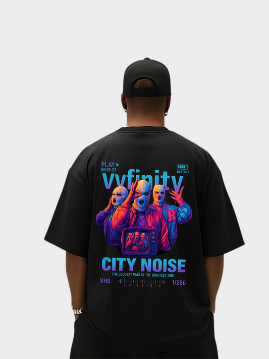 Vyfinity City Noise T-Shirt in Schwarz, Oversized Look, Rückseite, getragen von einem Model mit schwarzer Cap. Großes buntes Grafik-Design mit drei maskierten Figuren, Fernseher und Schriftzug City Noise.