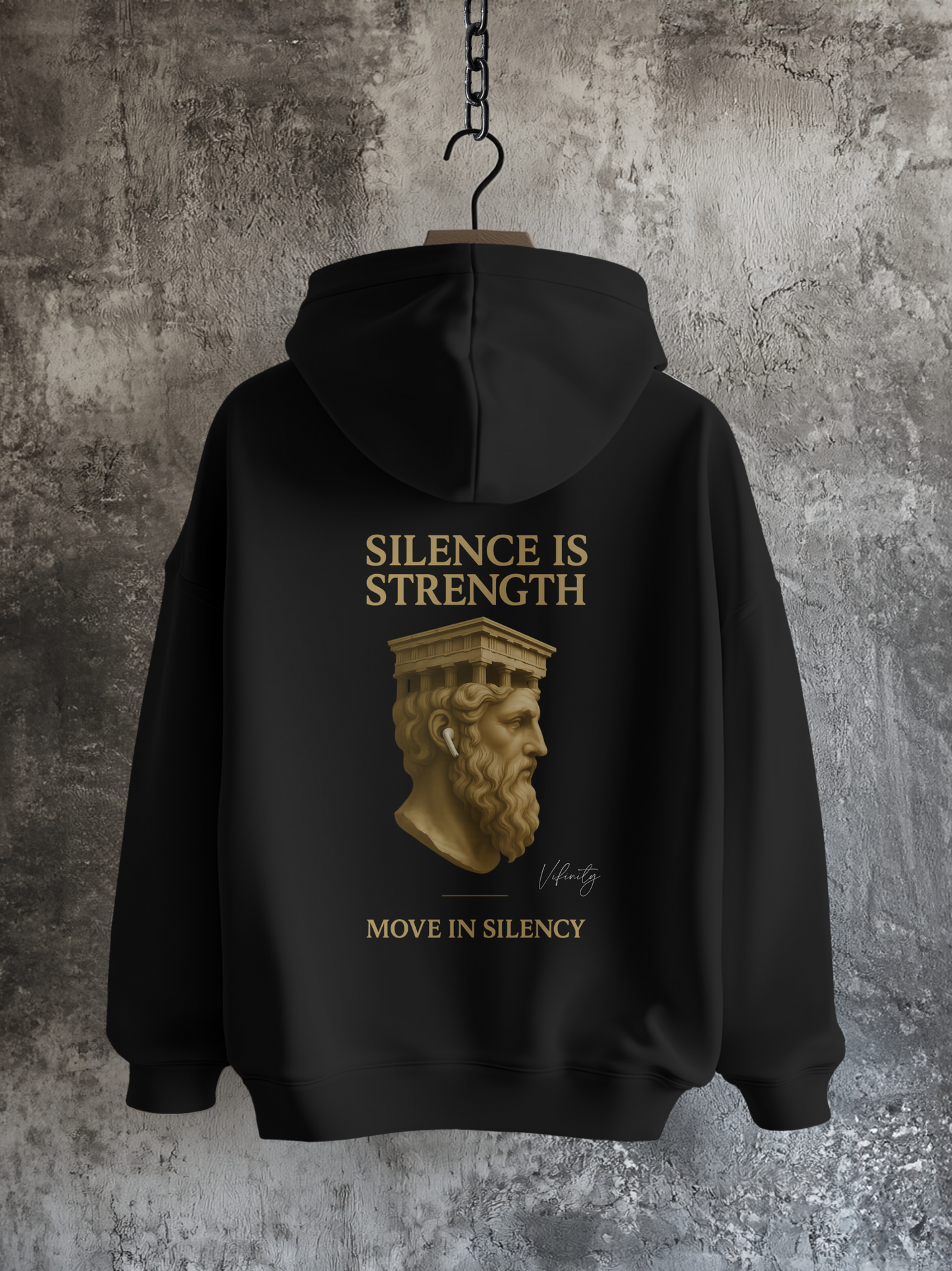 Vyfinity Move in Silency Hoodie mit goldener Statue und Claim „Silence is Strength“ – Rückansicht vor Betonwand