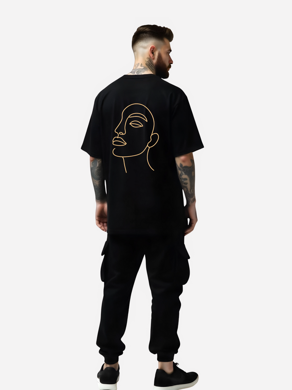 Vyfinity Oversize T-Shirt in Schwarz mit großem Line-Art Gesicht auf dem Rücken, getragen von tätowiertem Model in schwarzer Cargo-Jogginghose und Sneakers. Streetwear Outfit in Rückenansicht.