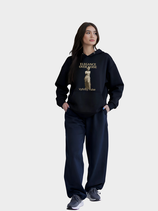 Frau trägt Vyfinity Pulse Hoodie in Schwarz mit Elegance Over Noise Design und goldener Statue