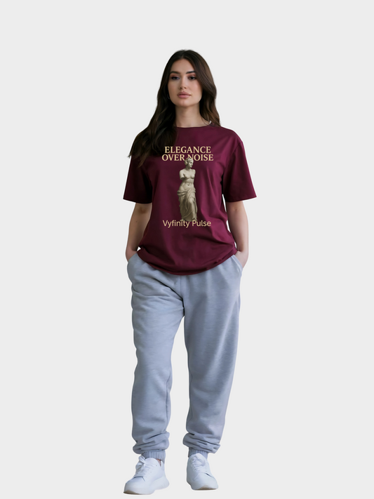 Model trägt burgundy Vyfinity Pulse T-Shirt Elegance Over Noise mit goldener Statue in Ganzkörperansicht
