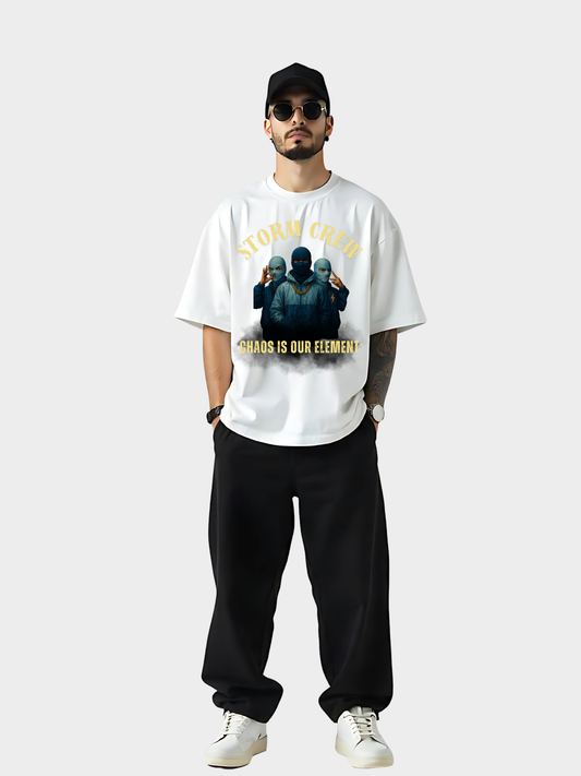 Vyfinity Storm Crew T-Shirt in Weiß, Frontansicht als Ganzkörper-Mockup. Model trägt schwarze Cap, Sonnenbrille, schwarze Hose und weiße Sneaker. Aufdruck zeigt drei maskierte Figuren mit goldener Aufschrift „Storm Crew“ oben und „Chaos is our element“ unten.