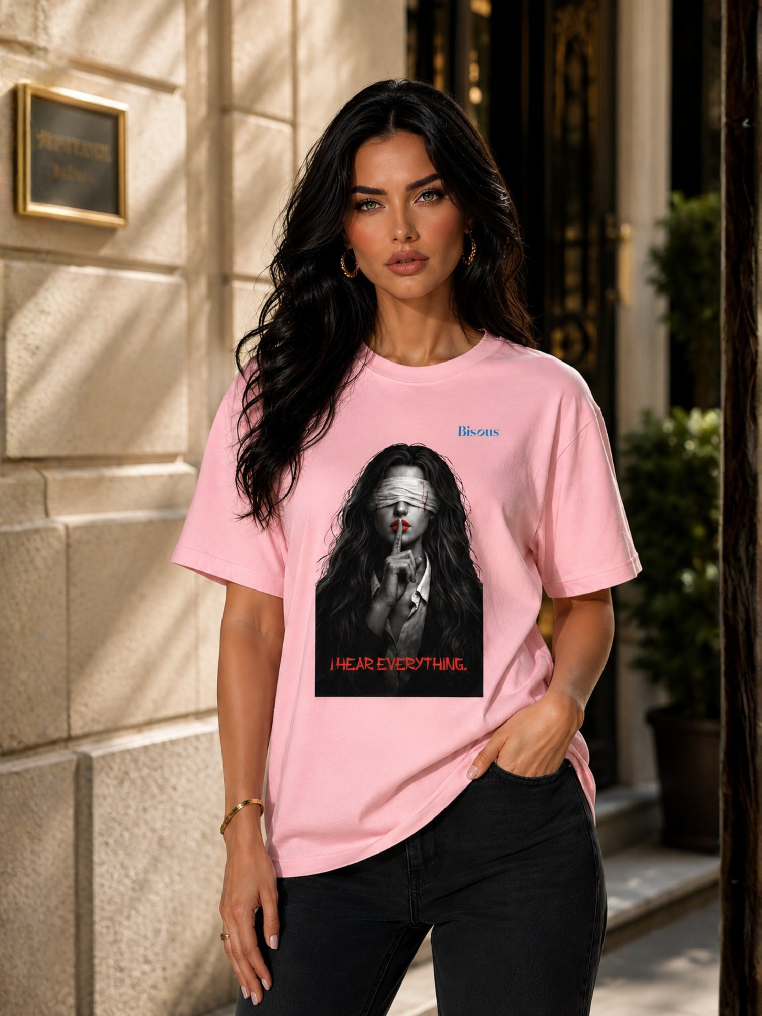 VYFINITY rosa Streetwear-T-Shirt an weiblichem Model mit „Bisous – I Hear Everything“ Frontprint, Blindfold-Frau-Motiv und schwarzer Jeans im urbanen Lifestyle-Look.