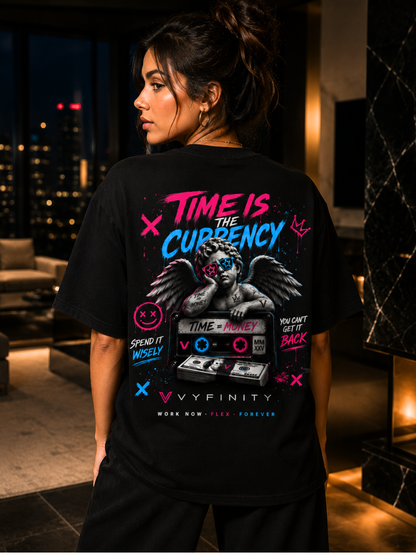 Frau trägt ein schwarzes VYFINITY Oversized Unisex T-Shirt mit großem „Time Is the Currency“ Rückenprint in einer luxuriösen modernen Penthouse-Wohnung bei Nacht. Streetwear Lifestyle mit auffälligem Urban-Art-Design, Engel, Kassette und Neonfarben in Pink und Blau.