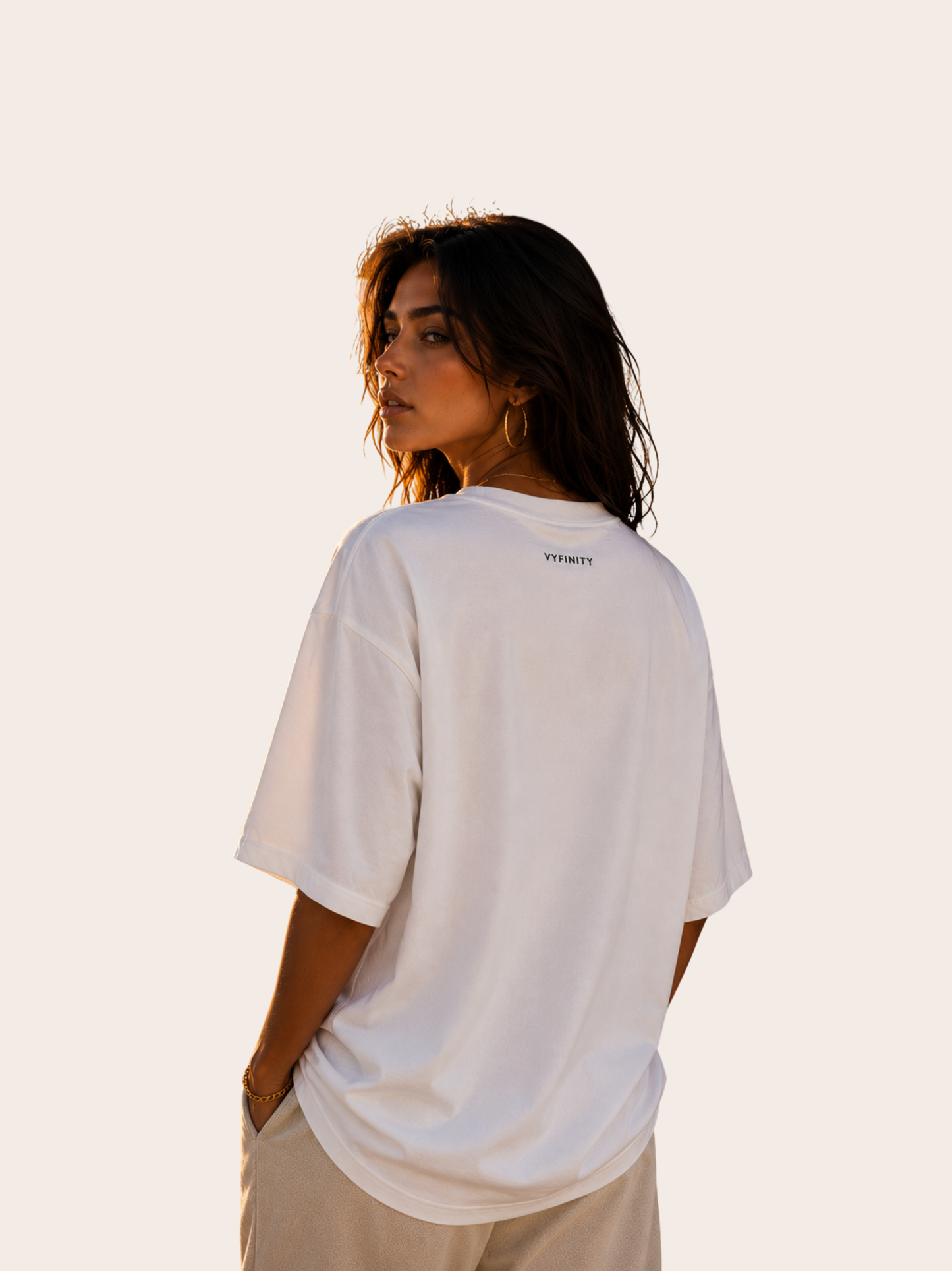 Junge Frau trägt ein weißes Vyfinity Relaxed Fit Unisex T-Shirt von hinten. Rückansicht mit dezentem Vyfinity Logo unter dem Kragen auf einem minimalistischen Premium Baumwollshirt im modernen Streetwear Stil.