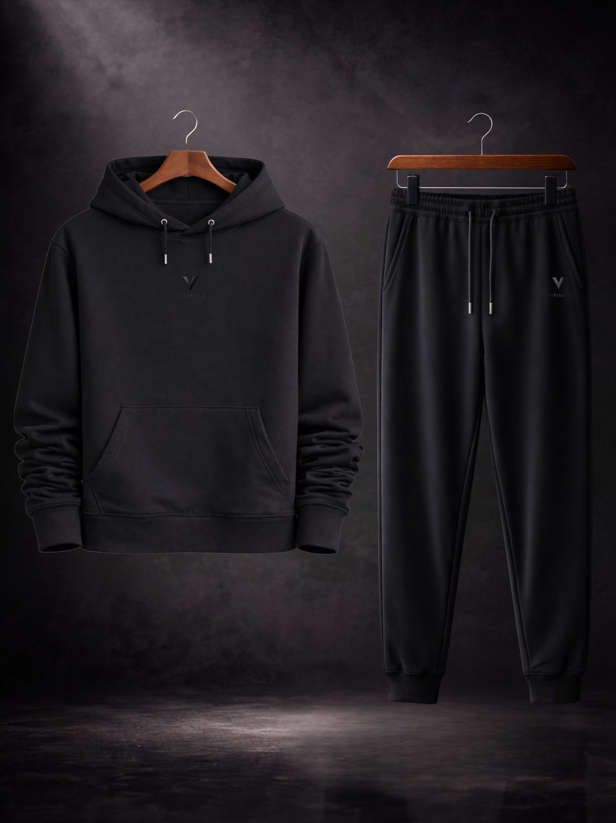 VYFINITY Black Edition Set mit schwarzem Oversized Hoodie und schwarzer Jogginghose auf Kleiderbügeln vor dunklem Studiohintergrund