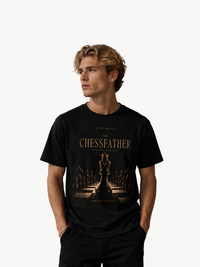 VYFINITY „The Chessfather“ schwarzes T-Shirt für Herren in Frontansicht mit goldfarbenem Schach-Design, Königsschachfigur und Schachbrett-Motiv, getragen von einem männlichen Model vor weißem Hintergrund.