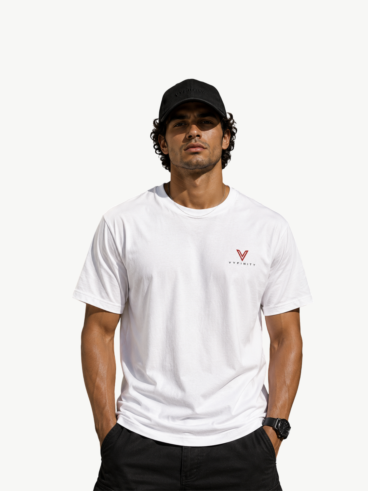 Männliches Model trägt ein weißes VYFINITY Premium T-Shirt im Relaxed Fit mit kleinem rot-schwarzem VYFINITY Logo auf der Brust und schwarzer VYFINITY Cap. Minimalistischer Streetwear-Look vor hellem Hintergrund mit klarer Sicht auf Passform und Vorderseite des Shirts.