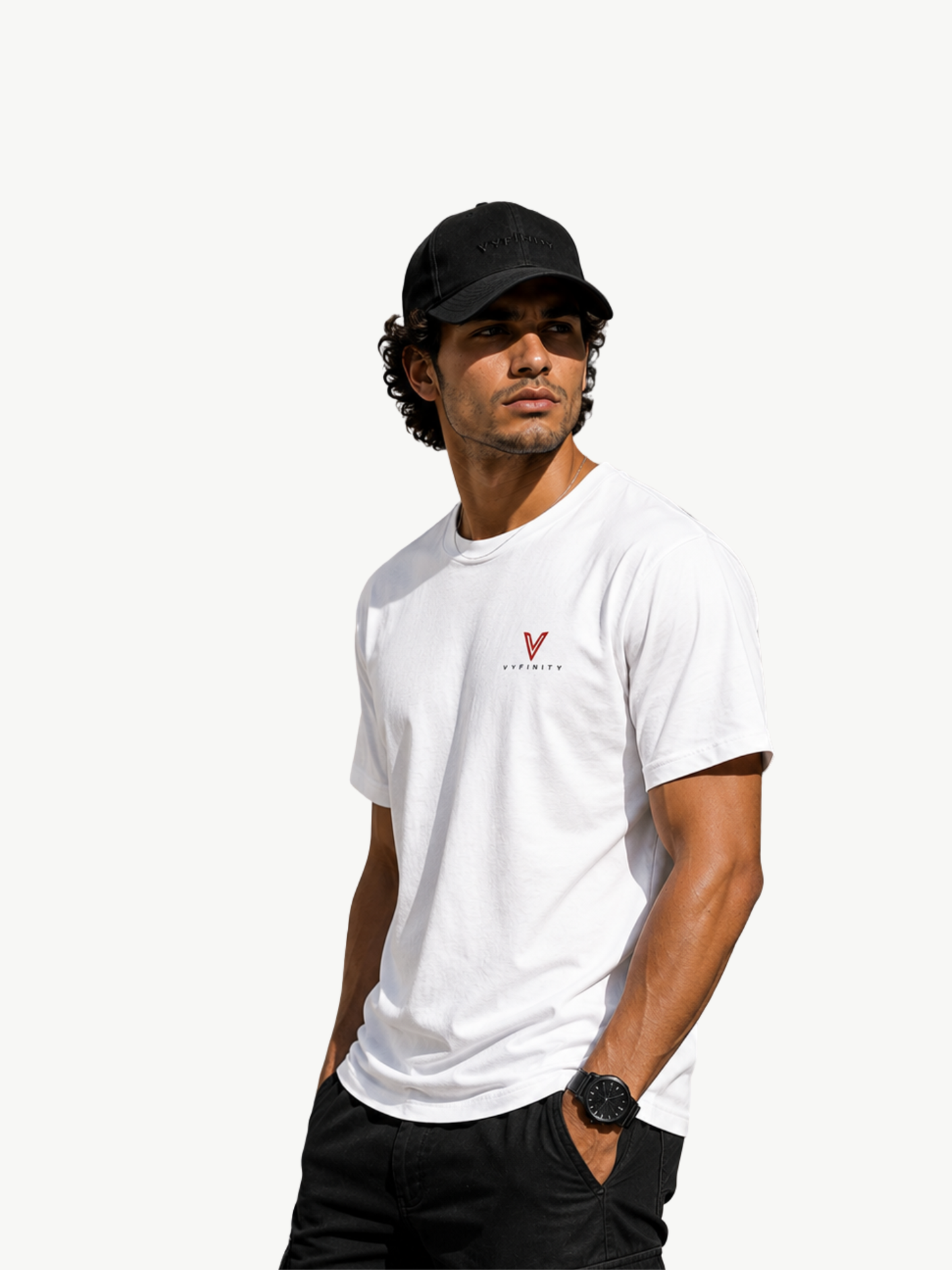 Männliches Model trägt ein weißes VYFINITY Premium T-Shirt im Relaxed Fit mit kleinem rot-schwarzem VYFINITY Logo auf der Brust und schwarzer VYFINITY Cap. Seitliche Lifestyle-Pose vor hellem Hintergrund zeigt Passform, Ärmel und hochwertige Streetwear-Optik des Shirts.