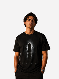 Junger Mann trägt ein schwarzes Vyfinity Classic Fit Unisex T-Shirt mit ECHO Frontprint. Premium Baumwollshirt mit dunklem Silhouettenmotiv und minimalistischem ECHO Schriftzug im modernen Streetwear und Urban Fashion Stil.