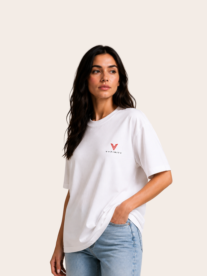 „Frau trägt weißes VYFINITY Relaxed Fit T-Shirt mit kleinem rotem VYFINITY Logo auf der Brust in seitlicher Pose.“