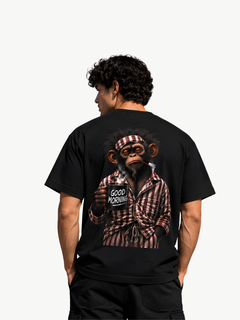 Männliches Model von hinten in schwarzem VYFINITY T-Shirt mit großem „Good Morning“-Affenmotiv auf dem Rücken. Der Affe trägt gestreiften Schlafanzug, hält eine dampfende schwarze Kaffeetasse und eine Zahnbürste im Mund. Heller, minimalistischer Hintergrund.