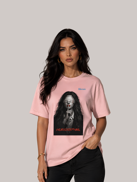 Brünette Frau trägt ein rosa Vyfinity Classic Fit Unisex T-Shirt mit künstlerischem Portrait-Print einer verbundenen Frau und dem Schriftzug „I Hear Everything“. Modernes Premium Streetwear-Lifestyle-Mockup mit hochwertigem Baumwollshirt und minimalistischer Fashion-Ästhetik.