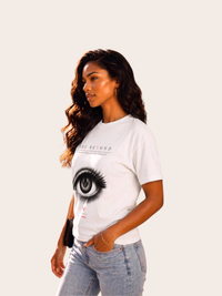 Weibliches Model in seitlicher Pose trägt ein weißes VYFINITY „SEE BEYOND“ T-Shirt mit großem schwarz-weißem Augenmotiv und dezenten roten Details, kombiniert mit hellblauer Jeans.