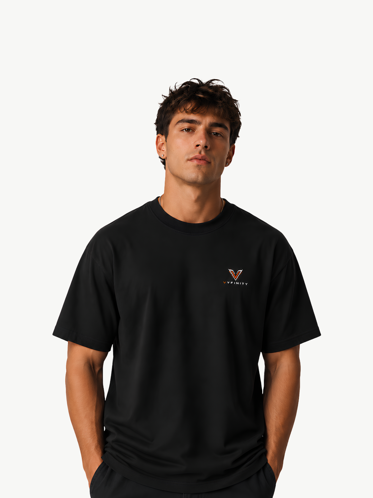 Männliches Model trägt ein schwarzes VYFINITY Heavy T-Shirt in Frontansicht. Auf der linken Brust befindet sich ein kleines VYFINITY-Logo in Weiß und Orange. Cleaner, minimalistischer Premium-Streetwear-Look vor hellem Studiohintergrund.