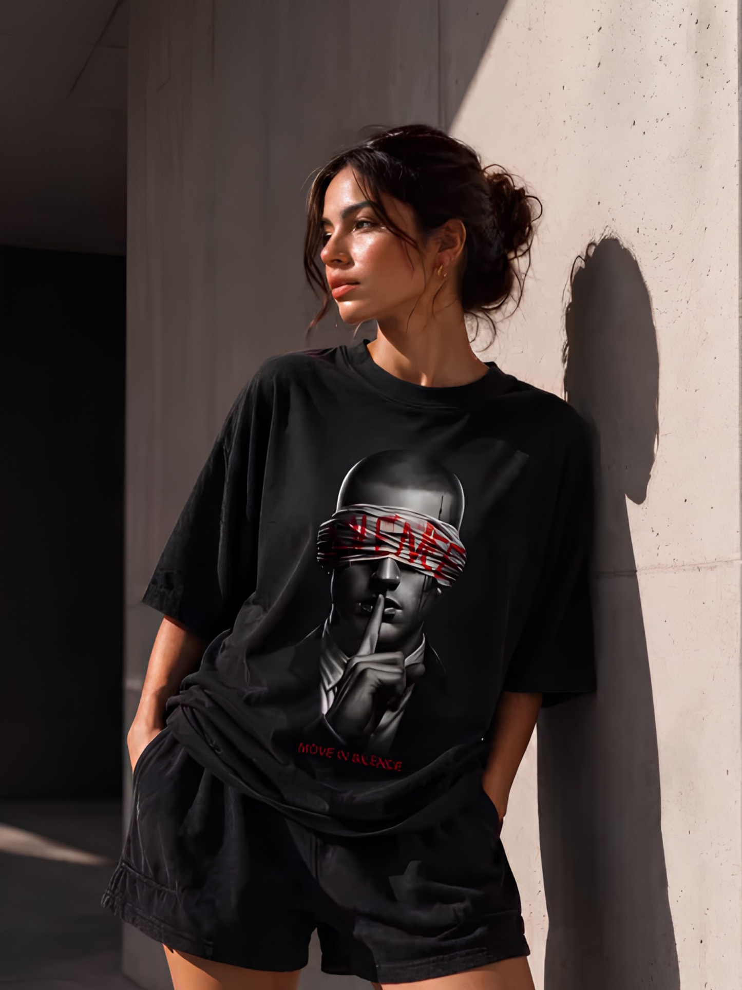 Lifestyle-Aufnahme einer Frau mit schwarzem Vyfinity Oversized-T-Shirt und markantem Frontprint. Das Statement-Motiv „MOVE IN SILENCE“ kombiniert minimalistisches Design mit hochwertiger Urban Streetwear für Damen und Herren.