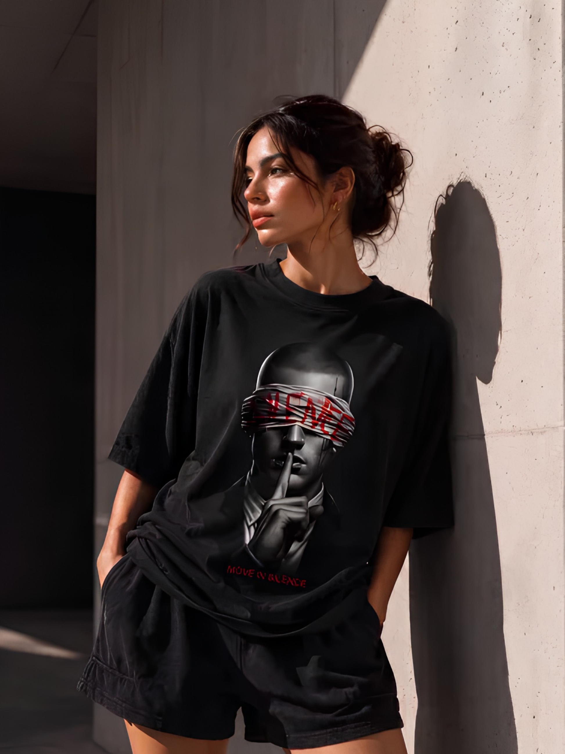 Lifestyle-Aufnahme einer Frau mit schwarzem Vyfinity Oversized-T-Shirt und markantem Frontprint. Das Statement-Motiv „MOVE IN SILENCE“ kombiniert minimalistisches Design mit hochwertiger Urban Streetwear für Damen und Herren.