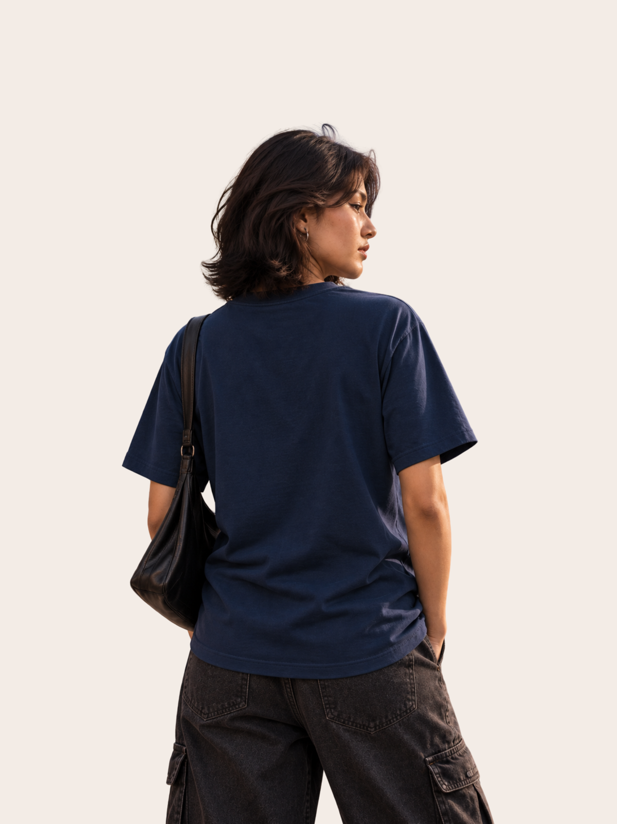 Damen Lifestyle-Mockup in Rückansicht mit navyblauem VYFINITY Regular Fit T-Shirt aus 180 GSM Baumwolle, kombiniert mit dunkler Cargo-Hose und schwarzer Schultertasche.