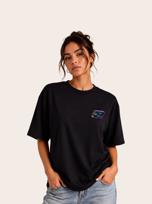 Frau trägt ein schwarzes VYFINITY Oversized Unisex T-Shirt mit kleinem „Time Is Money“ Brustlogo in Neonfarben. Modernes Premium Streetwear Mockup mit entspanntem Relaxed Fit auf neutralem Hintergrund – minimalistisches Fashion Design aus hochwertiger Bio-Baumwolle.