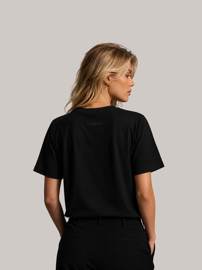 Rückansicht einer jungen Frau im schwarzen Vyfinity Classic Fit Unisex T-Shirt mit dezentem Vyfinity-Logo im Nacken. Minimalistisches Premium Baumwoll-T-Shirt ohne Rückenprint, zeitloses Streetwear-Design und eleganter Urban Fashion Look.