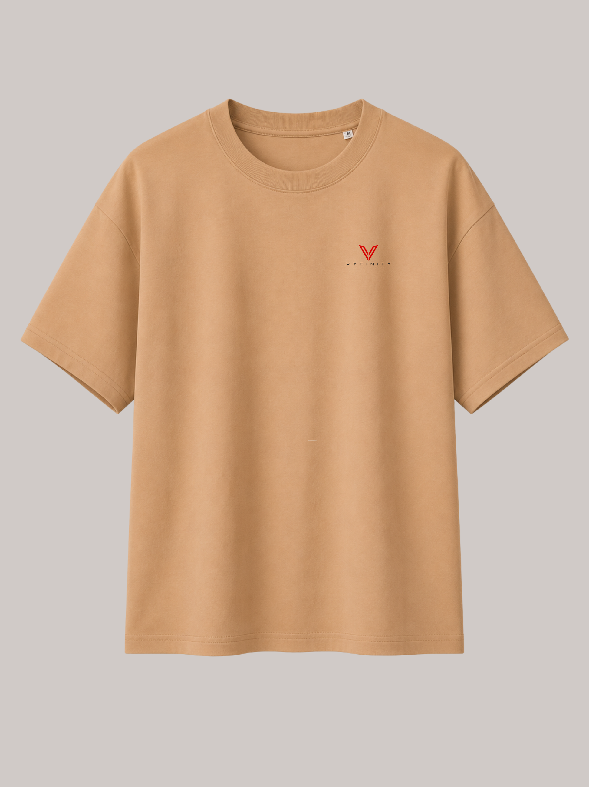 Beiges VYFINITY Oversized Unisex T-Shirt mit kleinem rotem VYFINITY Logo auf der linken Brust. Minimalistisches Premium Streetwear T-Shirt aus hochwertiger Baumwolle mit modernem Clean-Look für Damen und Herren.
