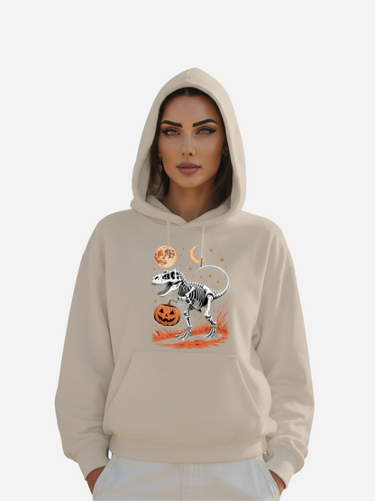 Frau trägt beigefarbenen Halloween Hoodie mit T-Rex-Skelett, Kürbis, Mond und Sternen Design.