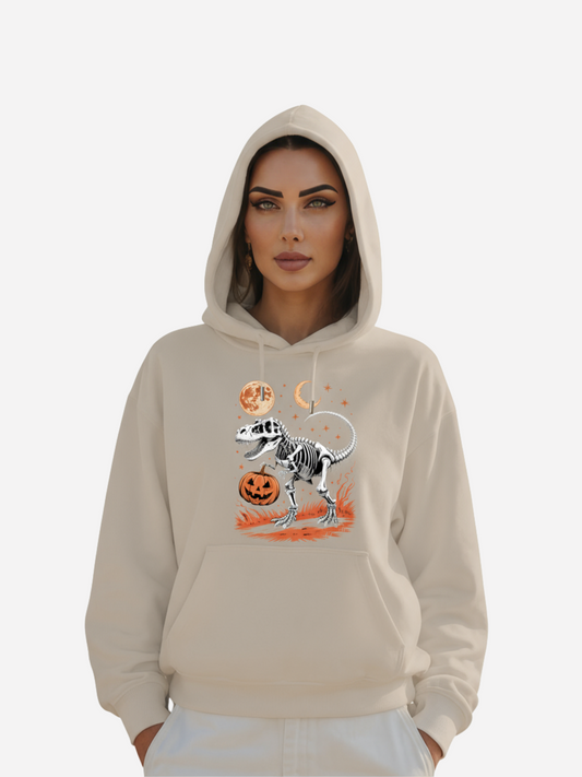 Frau trägt beigefarbenen Halloween Hoodie mit T-Rex-Skelett, Kürbis, Mond und Sternen Design.