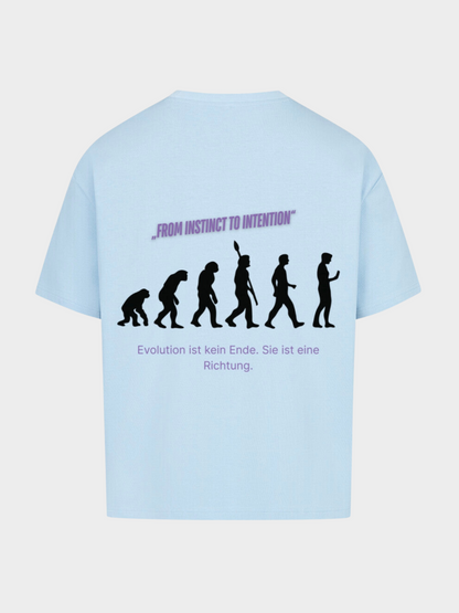 Oversized T-Shirt in Hellblau mit großem Rückenprint. Der Aufdruck zeigt die Evolution des Menschen als schwarze Silhouettenreihe, kombiniert mit dem violetten Spruch „FROM INSTINCT TO INTENTION“. Darunter steht: „Evolution ist kein Ende. Sie ist eine Richtung.“ Moderner Streetwear-Style mit Statement-Print.
