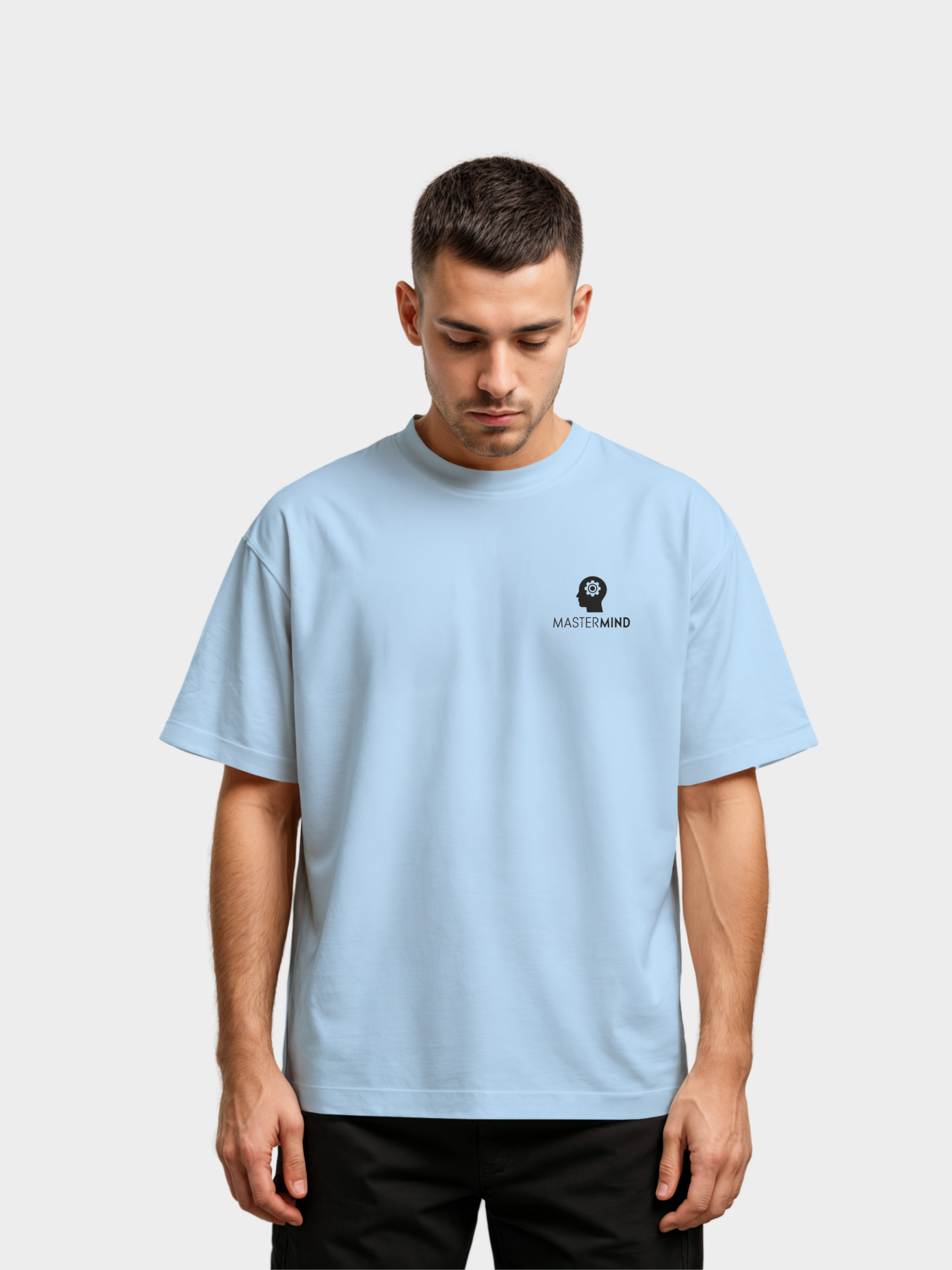 Oversized T-Shirt in Hellblau, getragen von einem Mann. Auf der linken Brust das schwarze Logo mit einem stilisierten Kopf und Zahnrad sowie der Schriftzug „MASTERMIND“. Moderner Streetwear-Look mit minimalistischem Frontdesign.