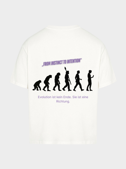 Oversized T-Shirt in Weiß mit großem Rückenprint. Schwarze Evolution-Silhouetten vom Affen bis zum modernen Menschen, darüber violetter Schriftzug „FROM INSTINCT TO INTENTION“. Darunter in Deutsch: „Evolution ist kein Ende. Sie ist eine Richtung.“ Modernes Streetwear-Design mit philosophischer Botschaft.