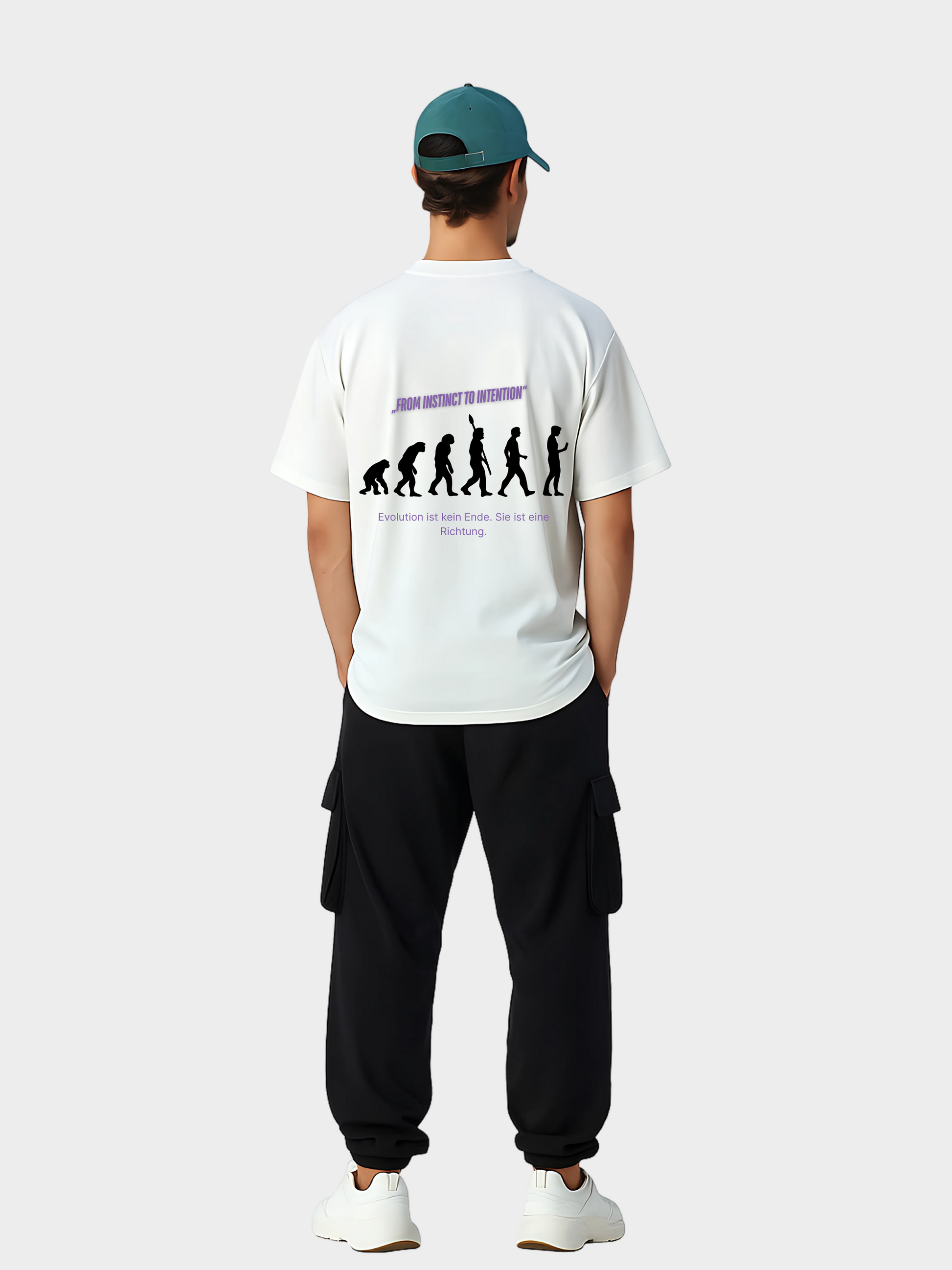 Oversized T-Shirt in Weiß mit Evolution-Grafik auf der Rückseite, getragen von einem Model mit grüner Cap, schwarzer Cargohose und weißen Sneakern. Das Rückendesign zeigt die Silhouette der Evolution vom Affen zum Menschen mit dem Schriftzug „FROM INSTINCT TO INTENTION“ in Violett und dem Zusatz „Evolution ist kein Ende. Sie ist eine Richtung.“