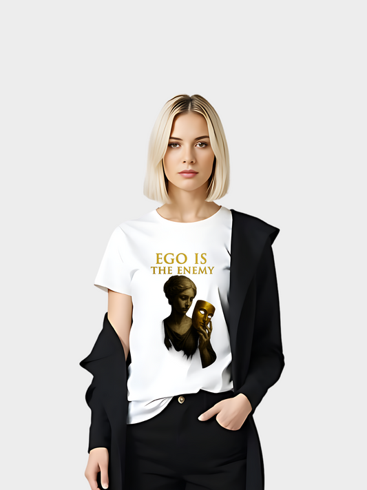 Weißes T-Shirt mit goldenem Aufdruck „EGO IS THE ENEMY“. Design zeigt eine antike Statue, die eine goldene Maske in der Hand hält. Modernes Streetwear-Shirt mit tiefgründiger Botschaft, kombiniert mit einem schwarzen Blazer für einen eleganten, urbanen Look.