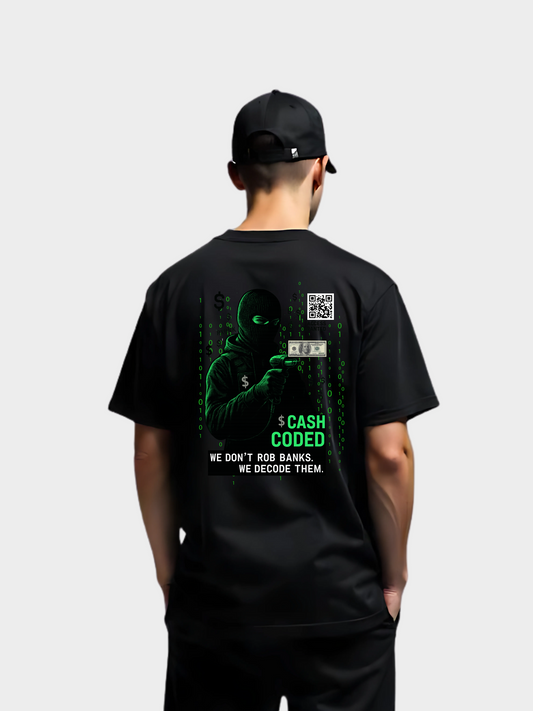 Rückansicht eines schwarzen Vyfinity T-Shirts „Cash Coded“ mit grünem Hacker-Design, QR-Code und Slogan „We don’t rob banks. We decode them.“ getragen von einem Model.