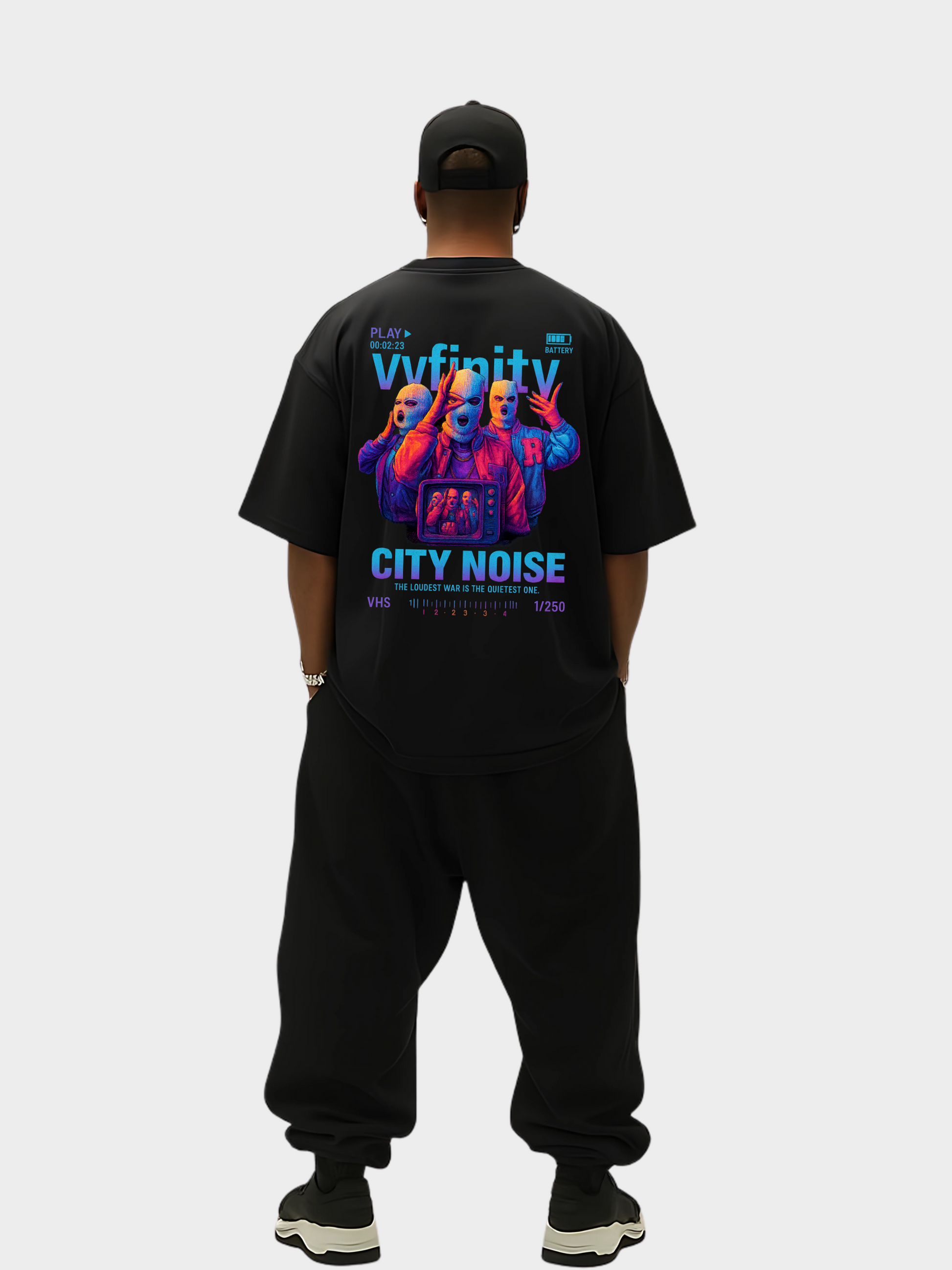 Vyfinity City Noise T-Shirt in Schwarz, Oversized Fit, Rückseite, getragen von einem Model in kompletter Streetwear-Ansicht. Auffälliger Rückenprint mit drei maskierten Figuren im VHS-Design und leuchtenden Farben. Limitierte Edition 1/250.