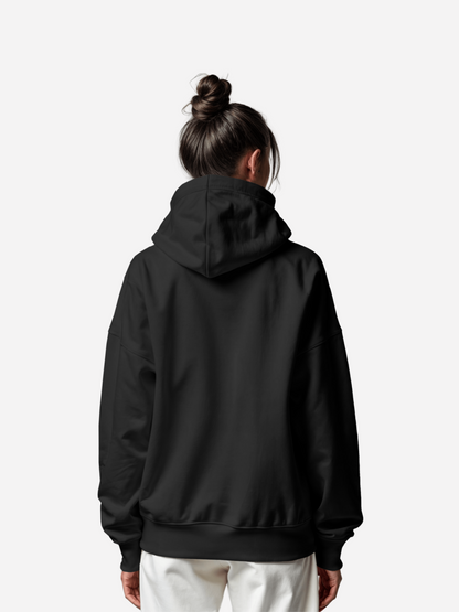 Rückansicht einer Frau im schwarzen Vyfinity Hoodie „The Closer“, schlichte Kapuze ohne Print, moderner Unisex Streetwear Look.