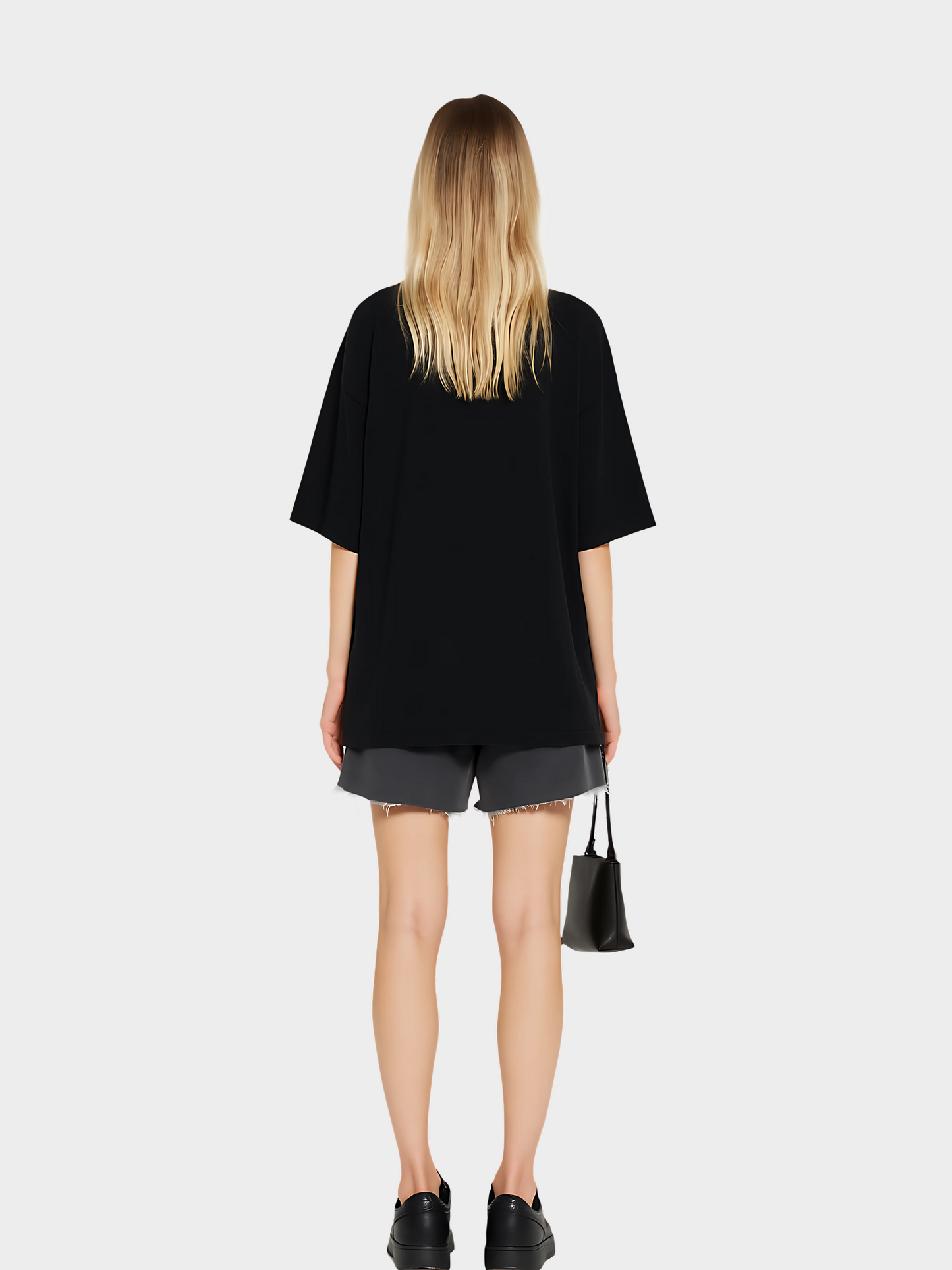Model zeigt die Rückseite des schwarzen Oversize Vyfinity T-Shirts ohne Print. Lässiger Streetwear-Look mit grauen Shorts, schwarzen Sneakern und kleiner Handtasche, minimalistisch und modern.
