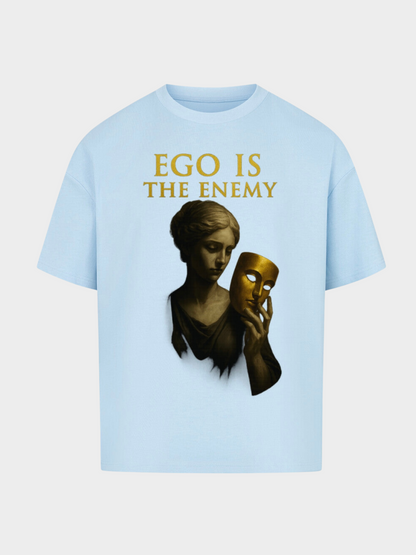 Hellblaues Oversize T-Shirt mit goldenem Schriftzug „Ego is the Enemy“. Design zeigt eine klassische Statue, die eine goldene Maske in der Hand hält – symbolisch für Wahrheit und Identität. Minimalistisches Streetwear Statement Piece.