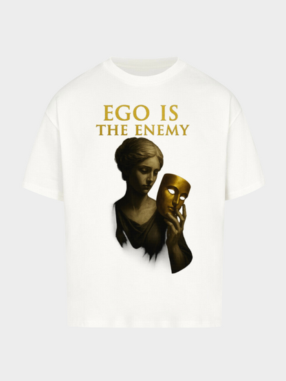 Weißes Oversize T-Shirt mit goldenem Schriftzug „Ego is the Enemy“. Kunstvolles Design mit einer klassischen Statue, die eine goldene Maske in der Hand hält – Symbol für Wahrheit, Identität und Demut. Minimalistisches Streetwear Statement Piece.