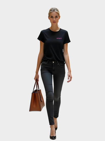 Vyfinity Logo T-Shirt in Schwarz mit pinkem Brustprint „Vyfinity“. Getragen von einem Model im modernen Streetwear-Look mit schwarzer Jeans und brauner Handtasche.