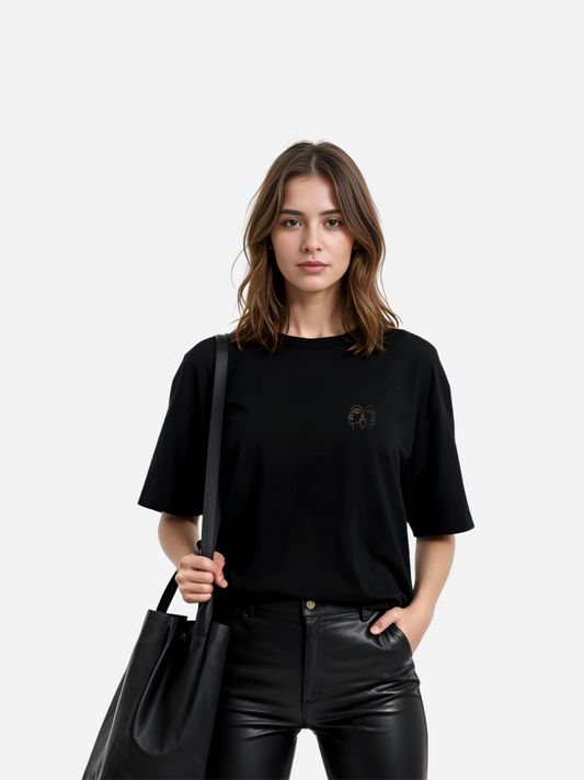 Vyfinity Oversize T-Shirt in Schwarz mit kleiner Line-Art Stickerei auf der Vorderseite, kombiniert mit schwarzer Lederhose und stylischer Schultertasche. Moderner Damen Streetwear Look mit minimalistischer Eleganz.