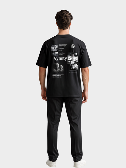 Schwarzes Oversize T-Shirt mit auffälligem Vyfinity Space Backprint. Design zeigt Astronauten, Planeten und kosmische Szenen in Schwarz-Weiß mit Textzitaten über Exploration und Menschlichkeit. Moderner Streetwear-Style mit urbanem Future-Look.