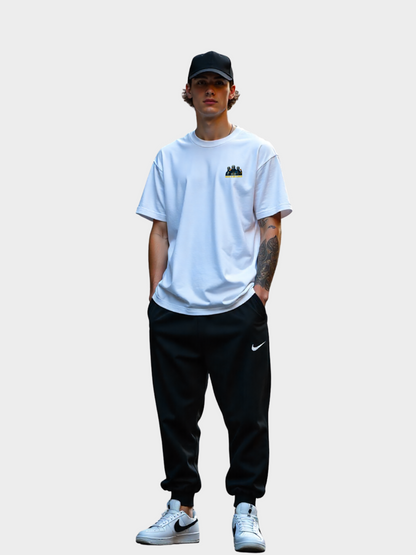Vyfinity Storm Crew T-Shirt in Weiß, Modelshot Frontansicht. Kleiner Brustprint mit drei maskierten Figuren, goldener Schrift „Storm Crew“ und dem Spruch „Chaos is our Element“. Lockerer Oversized Streetwear Look mit Cap und Joggerpants.